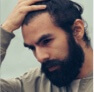 Profile picture of a bearded person stroking hand through his hair at the top of his head